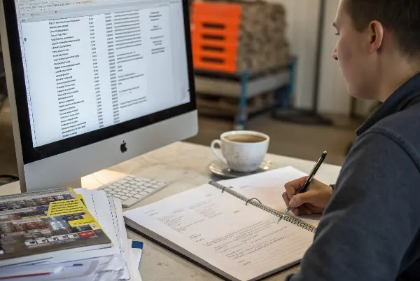 Engineer reviewing a product design on a computer with material datasheets nearby
